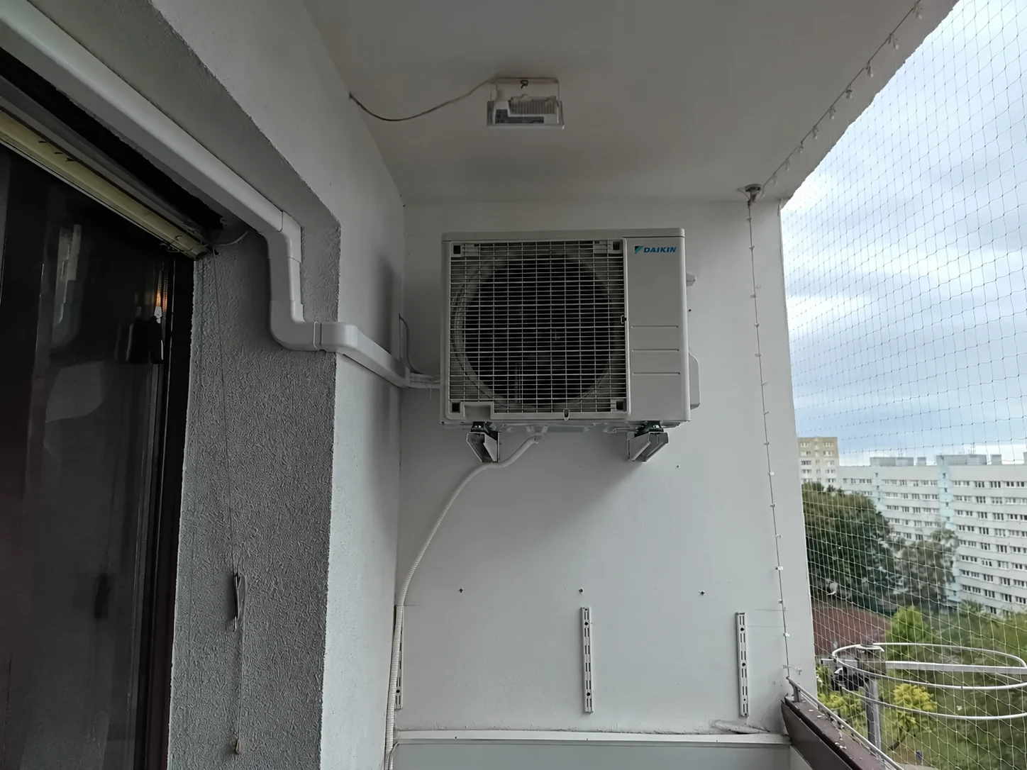 Agregat na wspornikach na balkonie z instalacją w korytku
